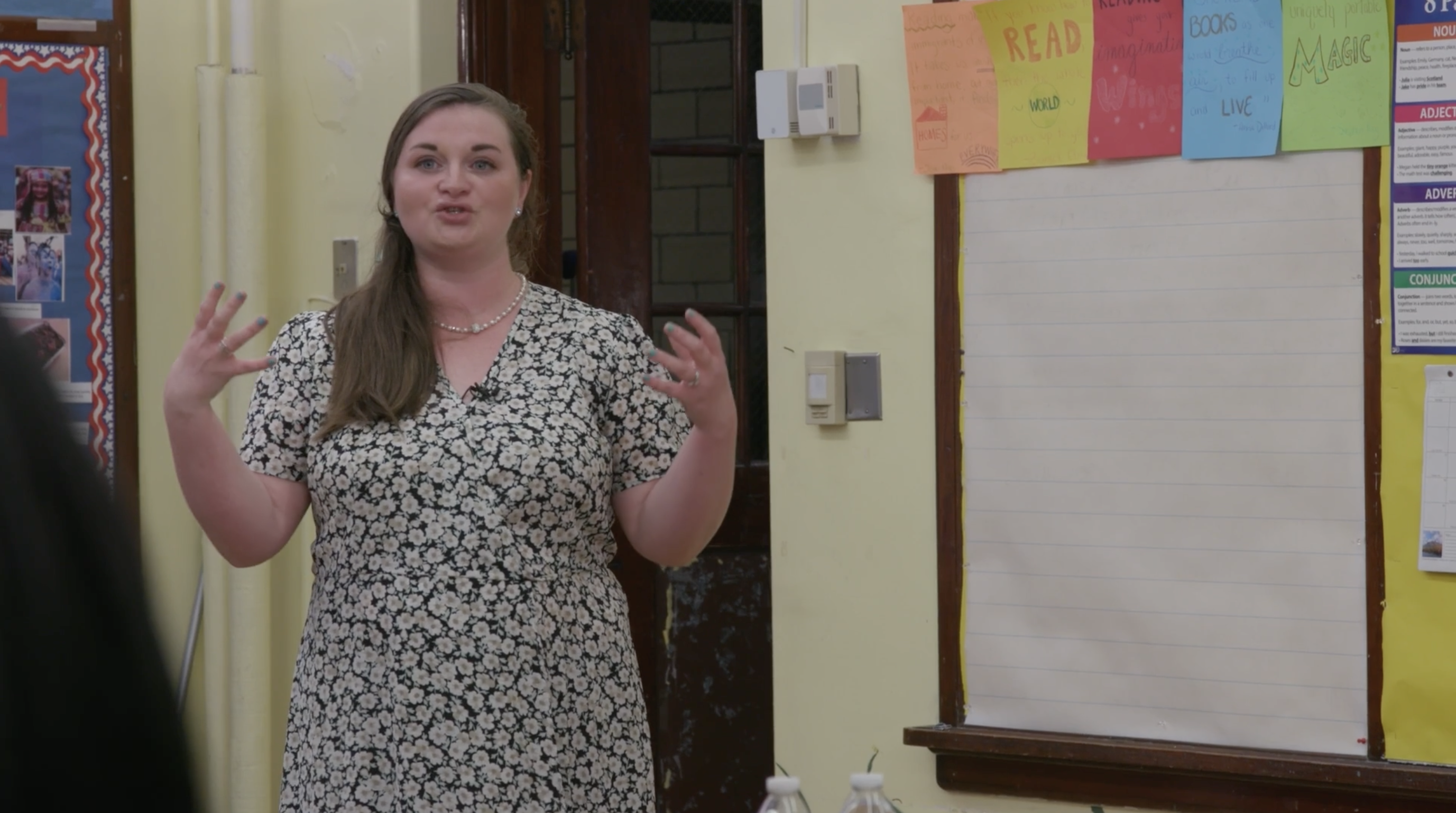screenshot of video: female teacher in front of class