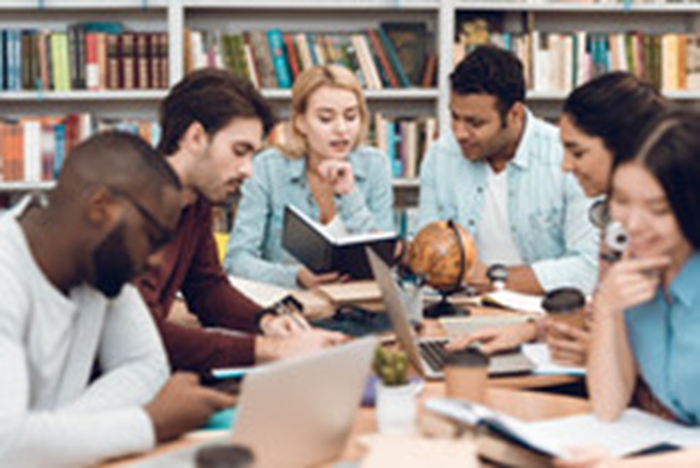 Six adult ed students around a table with textbooks and notebooks open. 