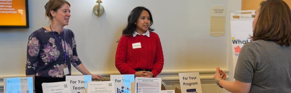 Directors Meeting 2026 - Two women staffing the SABES Program Support table with a third woman talking to them