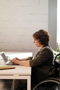 content woman in a wheelchair working on a laptop at a table